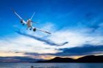 Commercial Airplane Flying Above The Sea At Sunset Stock Photo