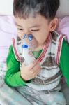 Asian Child Holds A Mask Vapor Inhaler For Treatment Of Asthma In Hospital Stock Photo