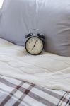 Modern Black Alarm Clock On Bed Stock Photo