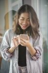 Asian Younger Woman Laughing With Happiness Emotion Looking And Message Chat On Smart Phone Stock Photo