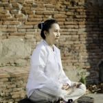 Asian Woman Meditating In Ancient Buddhist Temple Stock Photo