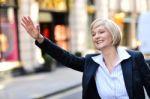 Businesswoman Raising Her Arm To Call A Taxi Stock Photo
