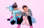 Happy Little Girls Holding  Unicorn Toys  Isolated On Pink Stock Photo