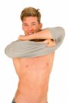 Smiling Young Man Removing T Shirt Stock Photo