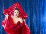 Mystic And Beautiful Young Woman In Red Silk On Blue Background Stock Photo