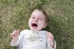 Child Crying And Lying On Grass Stock Photo
