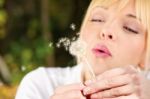 Blond Woman Blowing Flower Stock Photo