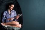 Relaxed Woman On Bubble Chair Reading Magazine Stock Photo