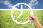 Hand Is Drawing A Clock On Lawns And Blue Sky Stock Photo