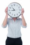 Woman Hiding Her Face Behind Wall Clock Stock Photo