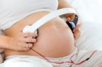 Pregnant Woman Putting Headphones On Her Belly Stock Photo