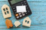 Calculator And Wood Houses On Wood Background Stock Photo