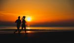 Young Couple: Man And Woman Run Together On A Sunset On Lake Coa Stock Photo