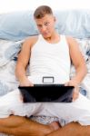 Man Working On Laptop In Bed Stock Photo