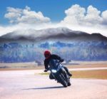 Young Man Riding Motorcycle On Asphalt Road Against Mountain Hig Stock Photo