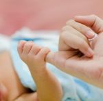 Baby Hand Holding Mother Finger Stock Photo