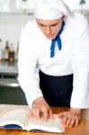 Male Chef Referring To Cooking Manual Stock Photo