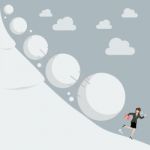 Business Woman Running Away From Snowball Effect Stock Photo