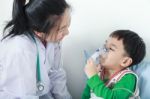 Asian Boy Having Respiratory Illness Helped By Health Professional With Inhaler Stock Photo