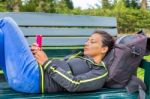 Dutch Woman Operating Mobile Phone Lying On Bench Stock Photo