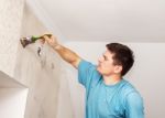 Worker Painting Wall With Background Glue For A Wallpaper Stock Photo
