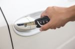 Closeup Of A Woman's Hand Inserting A Key Into The Door Lock Of A White Car Stock Photo