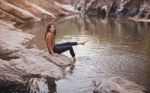 Young Woman On A River Bank Playing With Water Stock Photo