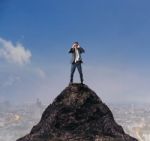 Young Business Man Standing On Top Of Mountain And Spying By Bin Stock Photo