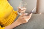 Beautiful Woman Holding A Glass Of Water And Using Smartphone Stock Photo