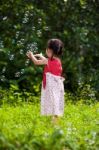 Asian Girl Catches Soap Bubbles On Nature Background. Outdoors Stock Photo