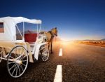 Horse And Classic Fairy Tale Carriage On Asphalt Road Perspective To Beautiful Land Scape With Sun Rising Sky Stock Photo