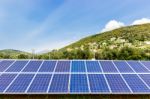 Blue Solar Collectors Near Town On Mountain Stock Photo