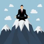 Businessman Meditating On A Mountain Peak Stock Photo