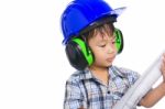 Young Boy Engineer With Blueprint, Wearing Earmuffs And Blue Helmet Stock Photo