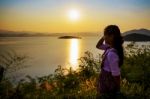 Happy Young Woman Standing Watching The Sunset Over The Lake Stock Photo