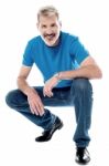 Handsome Man Crouching Down And Smiling Stock Photo
