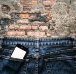 Blue Jeans With Cell Phone In A Pocket Background Stock Photo