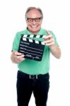 Bespectacled Elderly Man Holding A Clapperboard Stock Photo