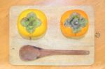 Two Persimmon And Wood Spoon On The Chopping Block Stock Photo