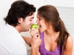 Closeup Of Young Couple Biting Green Apple Stock Photo