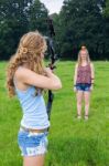 Girl Aiming Arrow Of Compound Bow At Apple On Head Of Woman Stock Photo