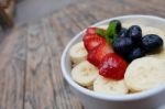 Acai Bowl With Fresh Fruit Strawberry, Blueberry, Banana And Peppermint Leaves On Top On The Wooden Table Stock Photo