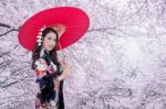 Beautiful Young Asian Woman Wearing Traditional Japanese Kimono With Red Umbrella And Cherry Blossom Stock Photo