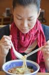 Young Woman Eating Noodles Stock Photo