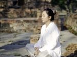 Asian Woman Meditating In Ancient Buddhist Temple Stock Photo