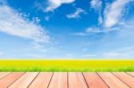 Blue Sky And Green Rice Field With Plank Wood Foreground Stock Photo