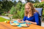 Young Caucasian Woman Eating Breakfast In Garden Stock Photo