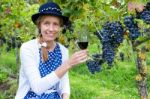 Caucasian Woman Toasting With Glass Of Wine Near Bunches Of Blue Stock Photo