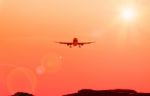 Airplane And Sunbeam With Lens Flare Effect On Orange Background Stock Photo