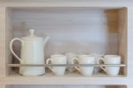 Teapot And Cups On Wooden Shelf Stock Photo